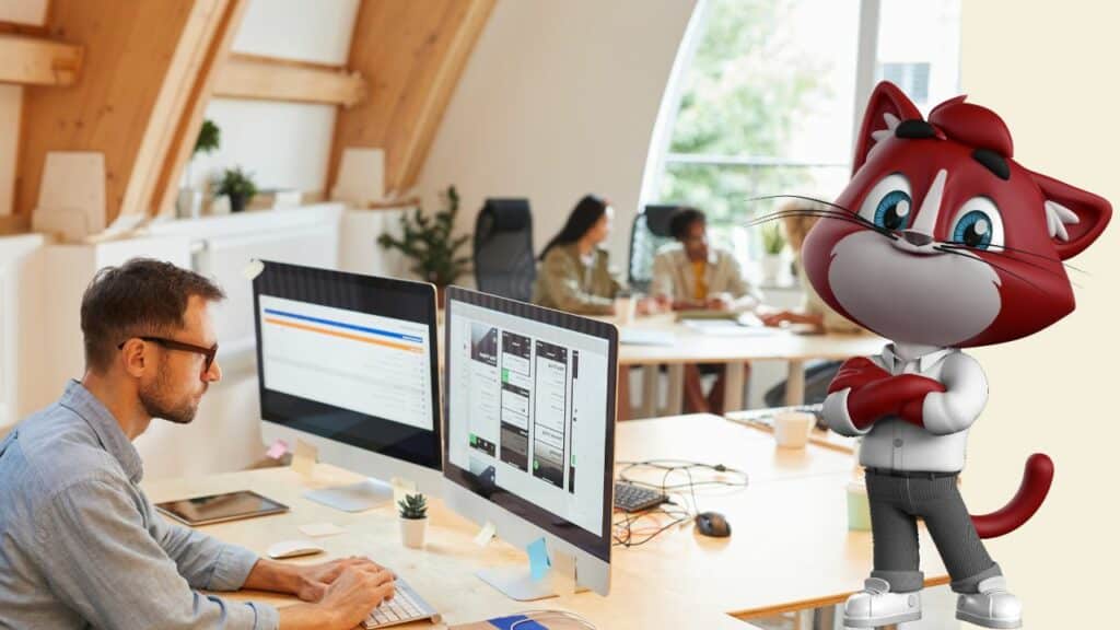 Un homme travaille sur un double écran dans un bureau lumineux, pendant qu’une équipe échange en arrière-plan ; une mascotte de chat professionnelle apparaît à droite, bras croisés, en posture confiante.